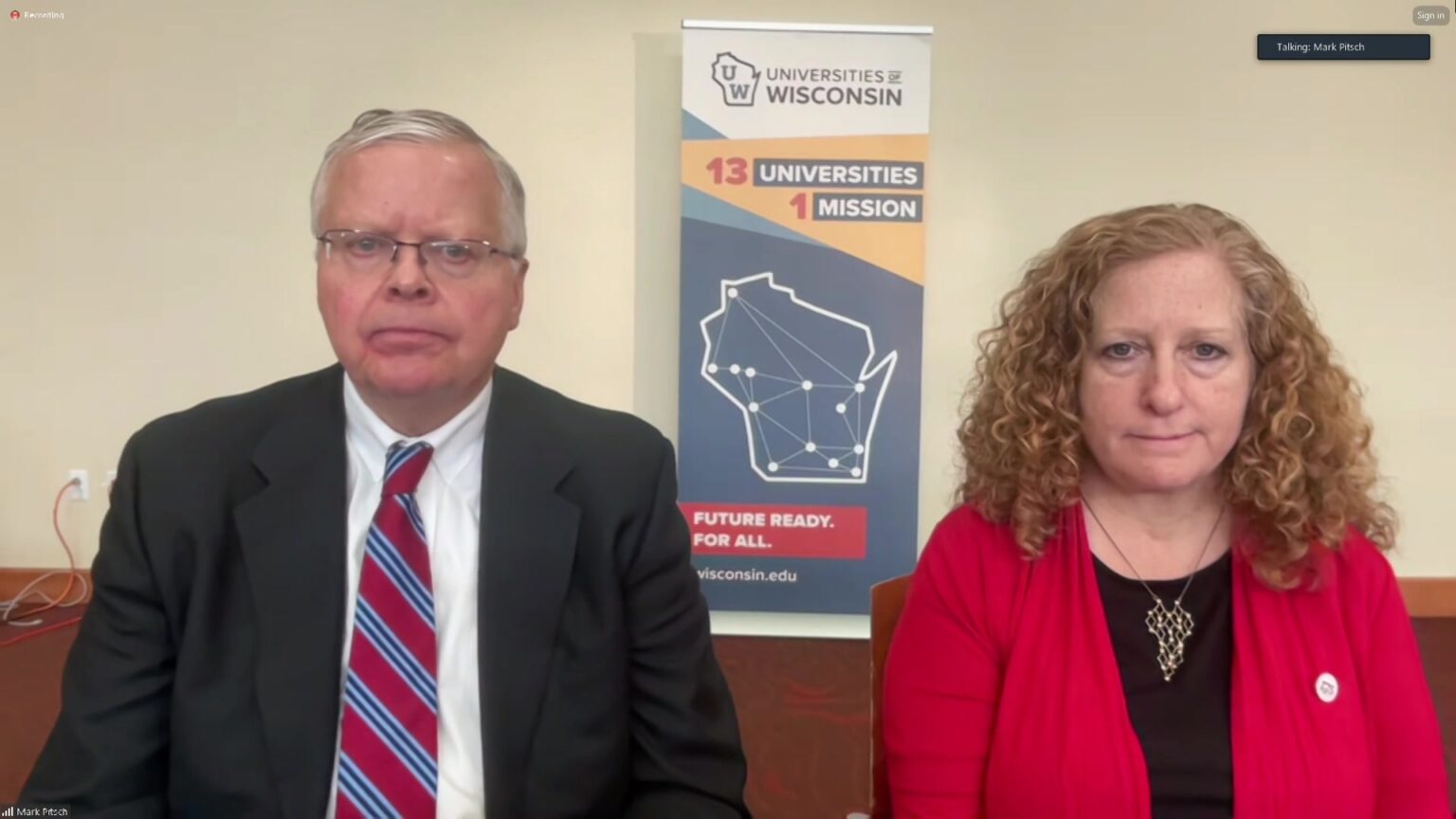 A still image from a video livestream shows Jay Rothman and Jennifer Mnookin seated in a room, with a banner in the background showing the Universities of Wisconsin wordmark and the words 13 universities, 1 mission and Future Ready. For All. with an outline of the state showing the location of each campus connected by lines.