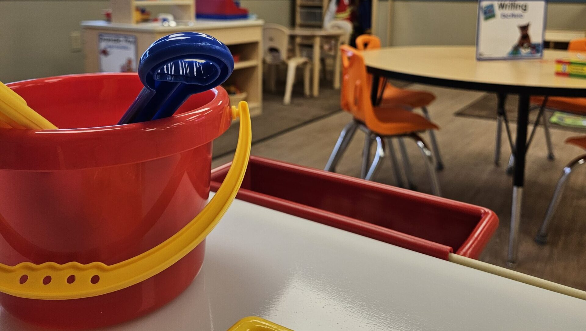A photo of an early learning classroom with toys, tables, chairs, and books.