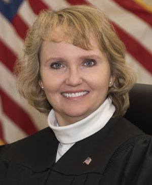 Shelley Grogan poses for a portrait in front of a U.S. flag while wearing judicial robes.