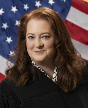 Maria Lazar poses for a portrait in front of a U.S. flag while wearing judicial robes.