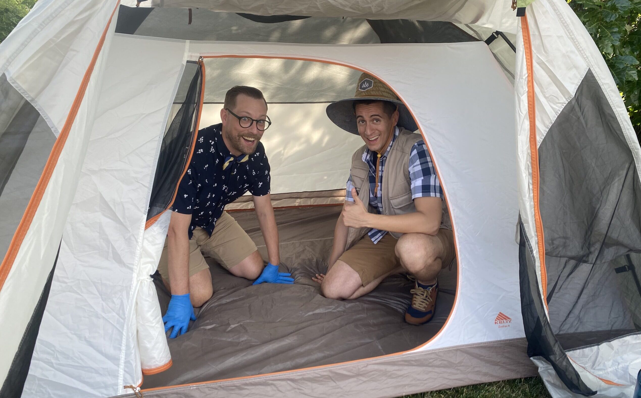 Two people in a tent smile out at the camera.