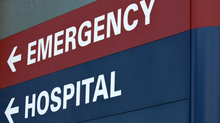 A large exterior panel sign shows the words Emergency and Hospital with arrows pointing left.