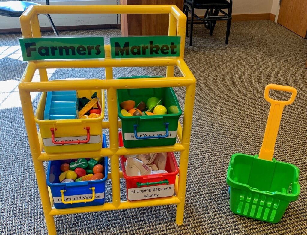 A pretend farmers market is set up in a library space.