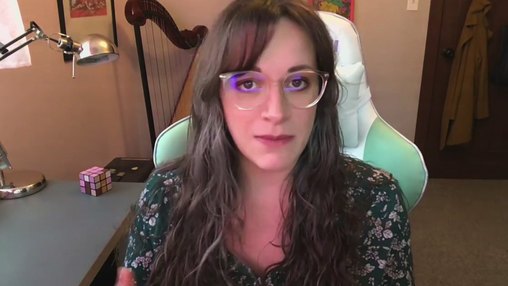 A still image from a video conference shows Kristina LaPlant sitting next to a table with a lamp and a harp in the background.