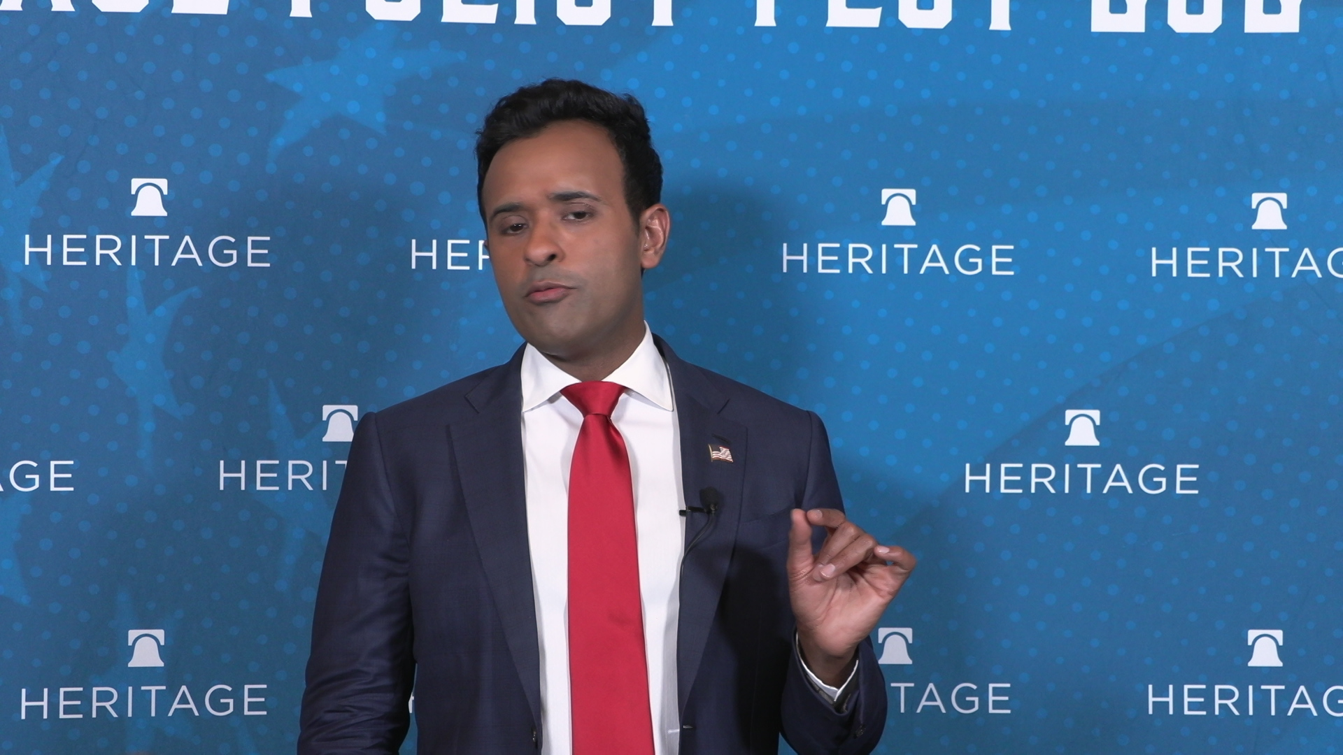 Vivek Ramaswamy stands in front of a backdrop with the words 'Heritage' printed in the background.