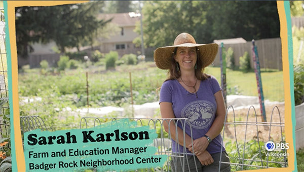 The Wisconsin Gardener guest Sara Karlson stands behind a fence in a large garden.