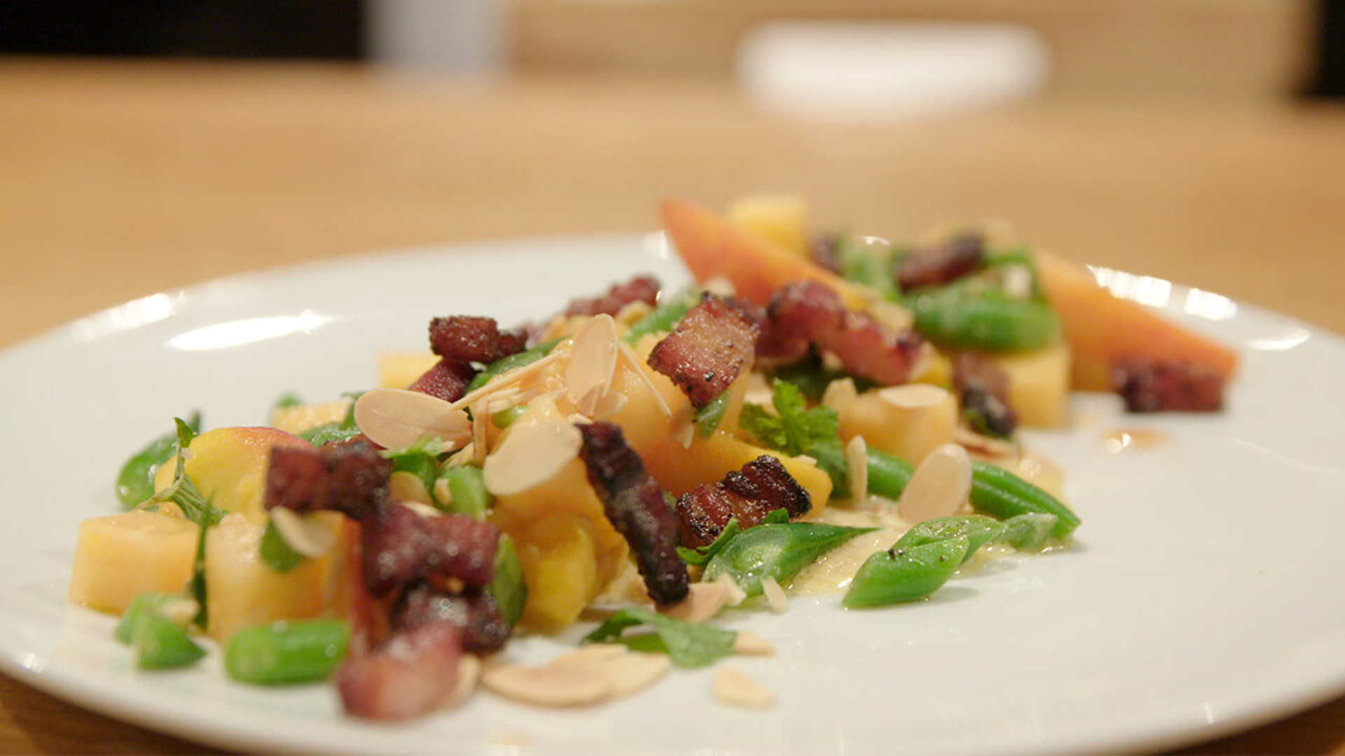 Plate with salad of green beans, bacon and peaches.