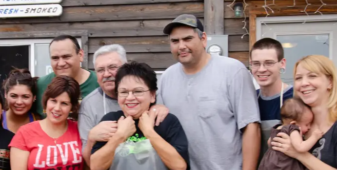 8 family members stand together smiling at the camera.