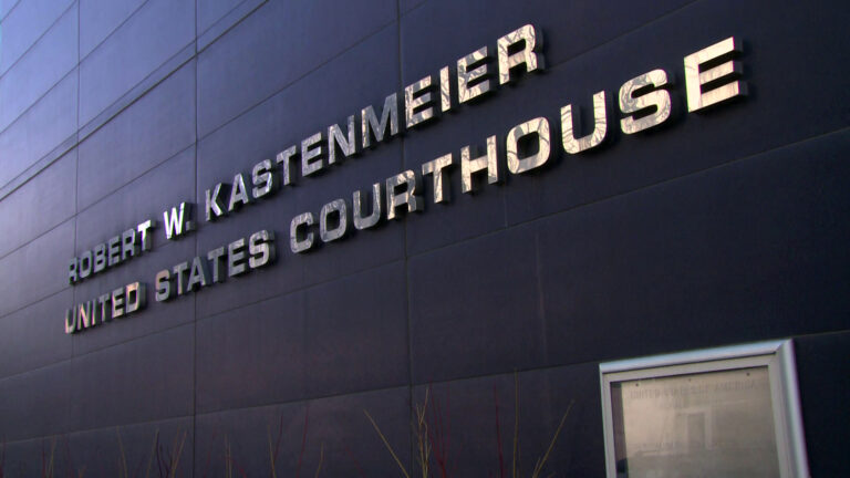 Letters affixed to the sign of a metal-paneled building read Robert W. Kastenmeier United States Courthouse.