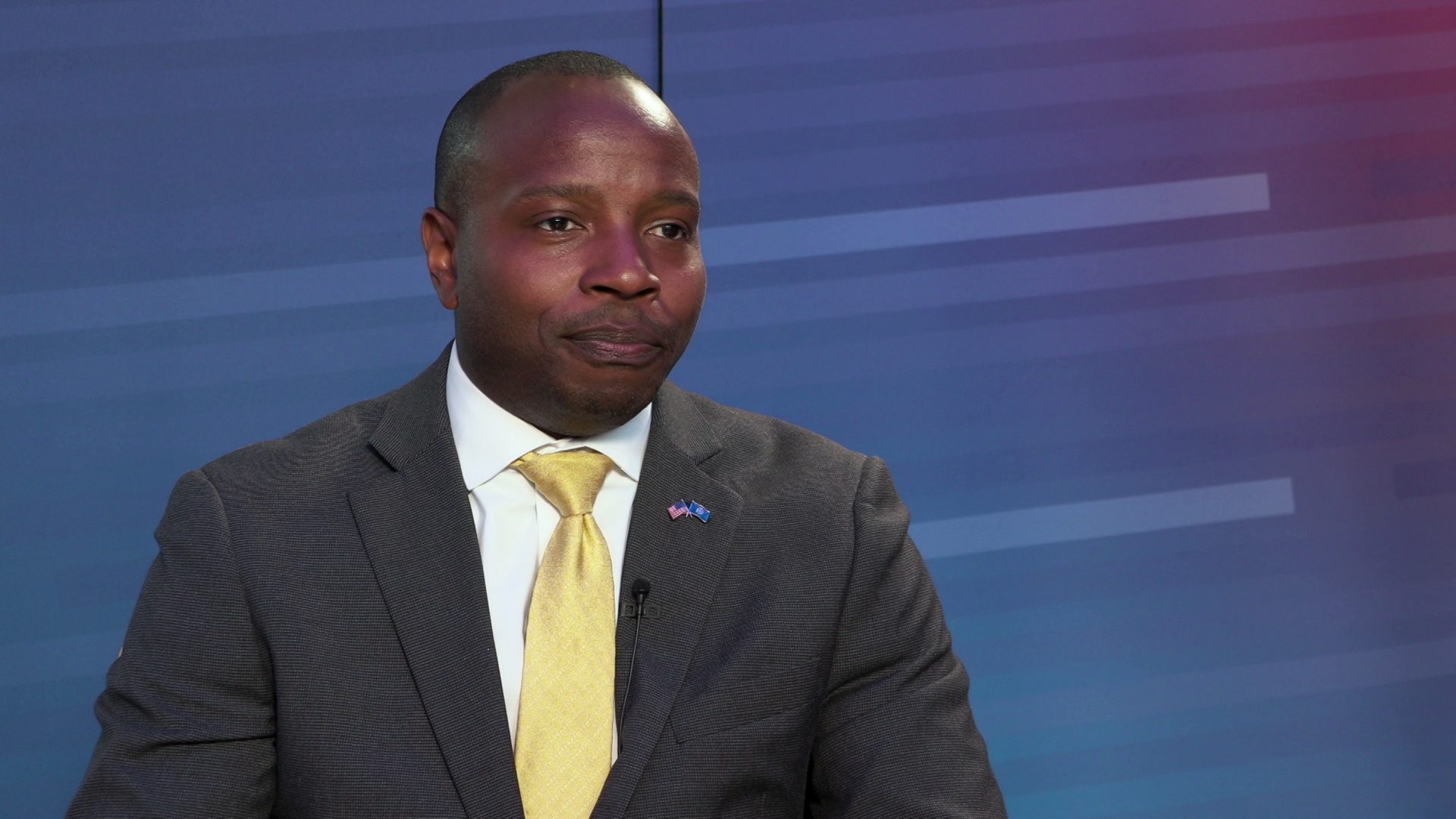 Cavalier Johnson speaks while sitting in front of a gradient background.