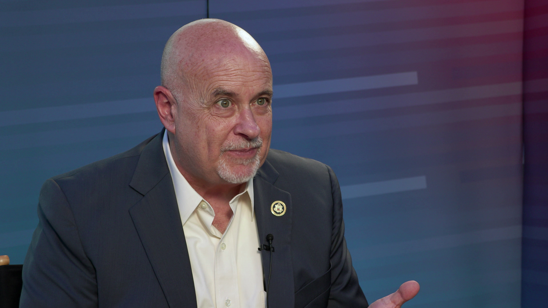 Mark Pocan speaks while sitting in front of a gradient background.