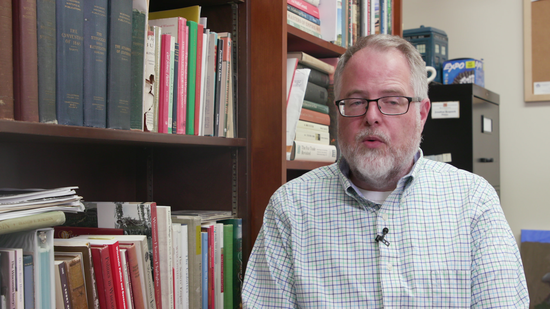 Jonathan Kasparek sits and speaks with books lining bookshelves in the background.