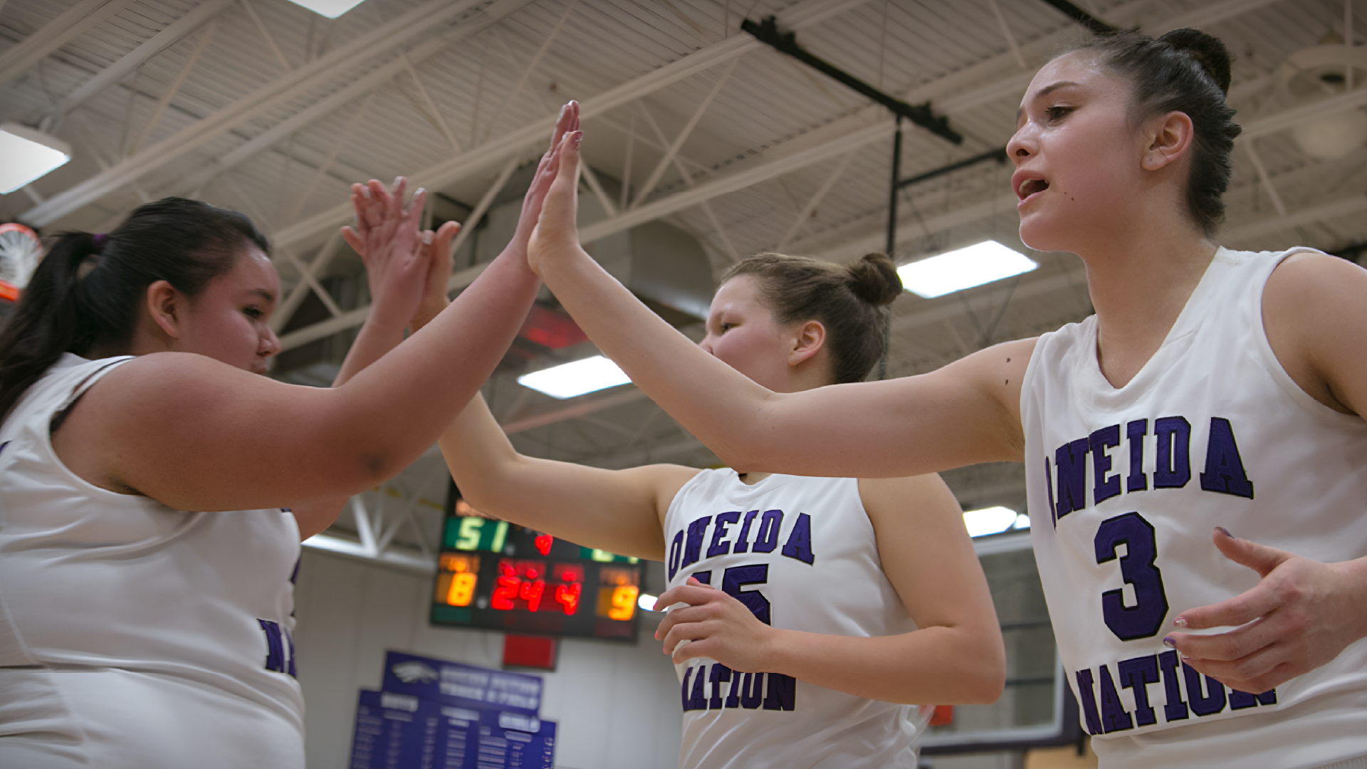 High school girls basketball team high fives one another.