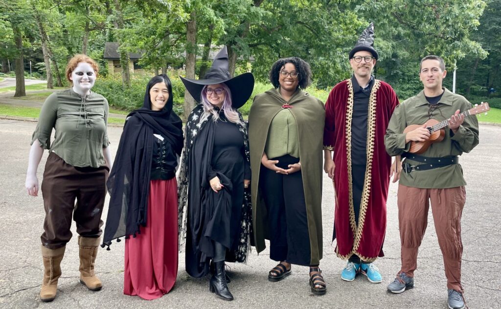 Six people stand together outside, dressed in various fantasy costumes.