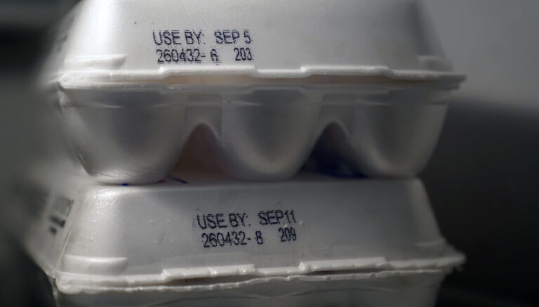 Two stacked polystyrene foam egg cartons have USE BY: date stamps their sides.