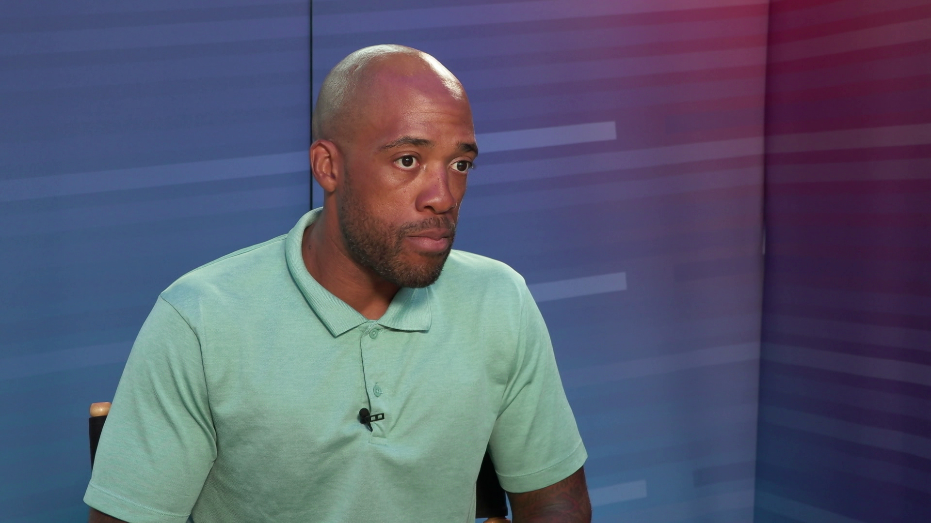 Mandela Barnes speaks while sitting in front of a gradient background.