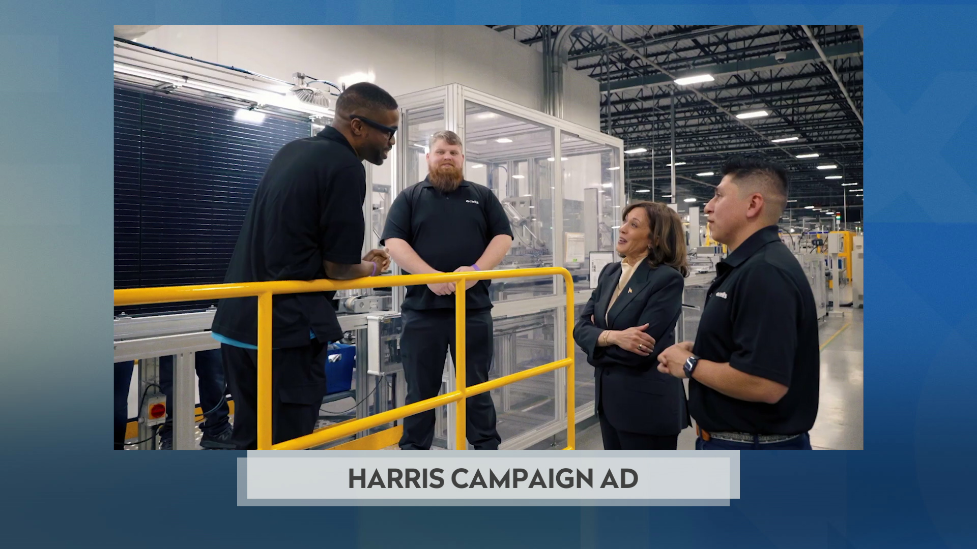 A still image from a political television commercial shows Kamala Harris standing next to someone and two others who are standing over a railing in a high ceiling industrial warehouse, with a graphic at bottom reading "Harris Campaign Ad."