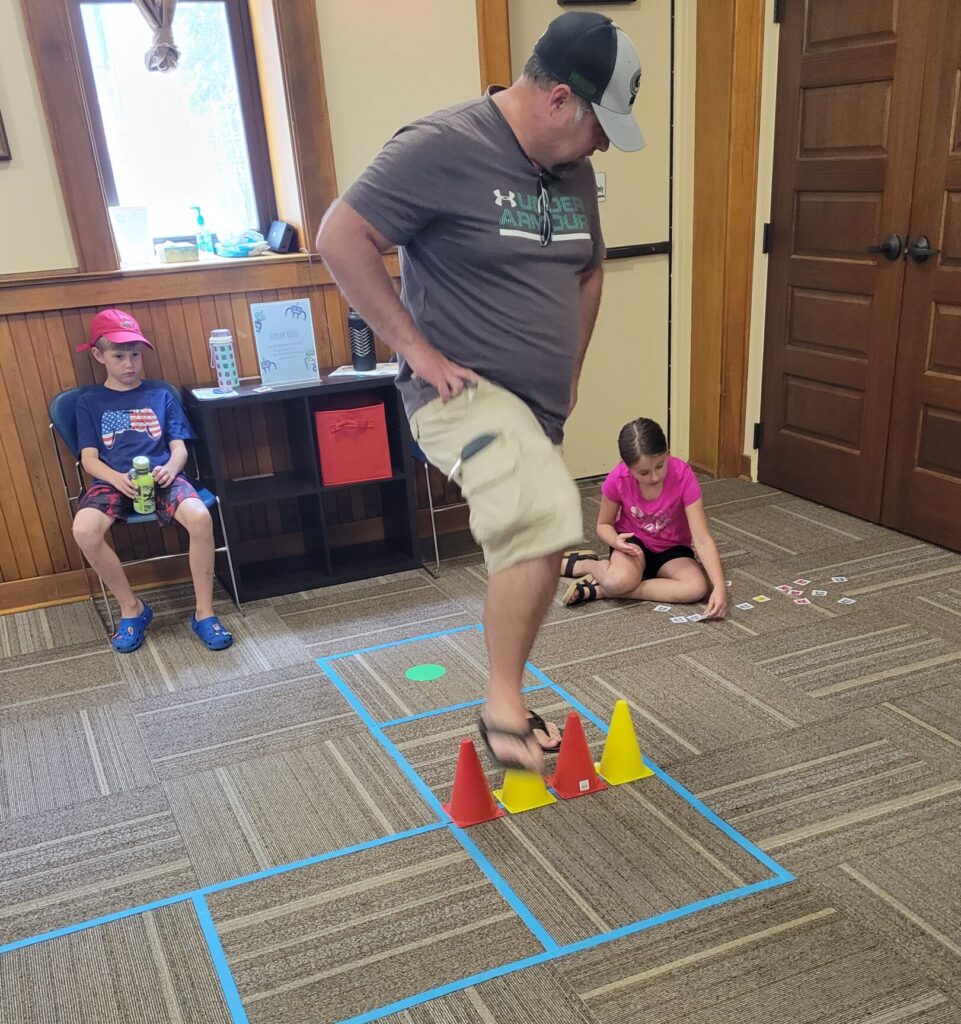 A child and adult in a library room play a coding game together.