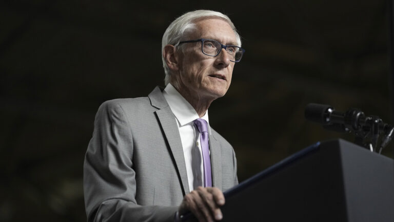 Tony Evers speaks while standing at a podium with a microphone mounted to its top.