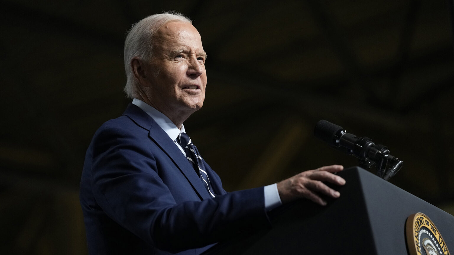 Joe Biden speaks while standing at a podium with a microphone mounted to its top and the Seal of the President of the United States of America affixed to its front.