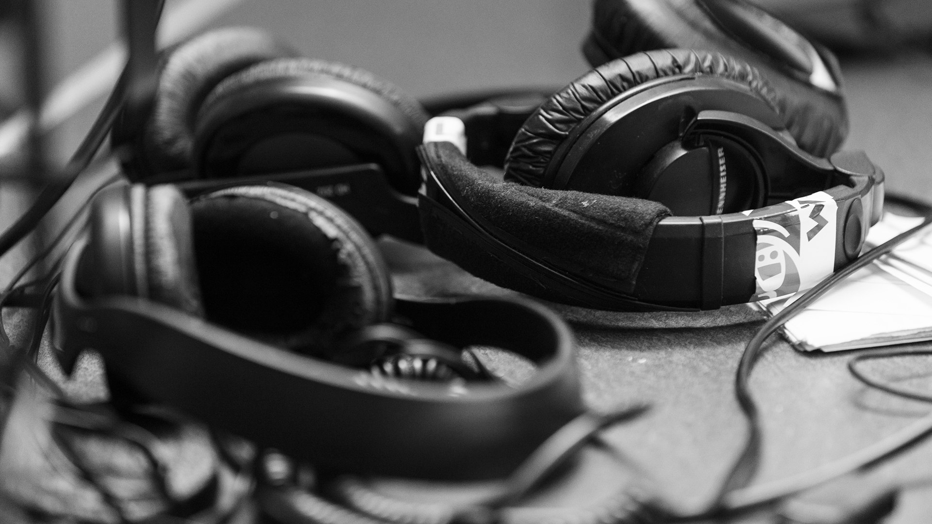 Two sets of studio headphones sit on their sides amid a tangle of cords.