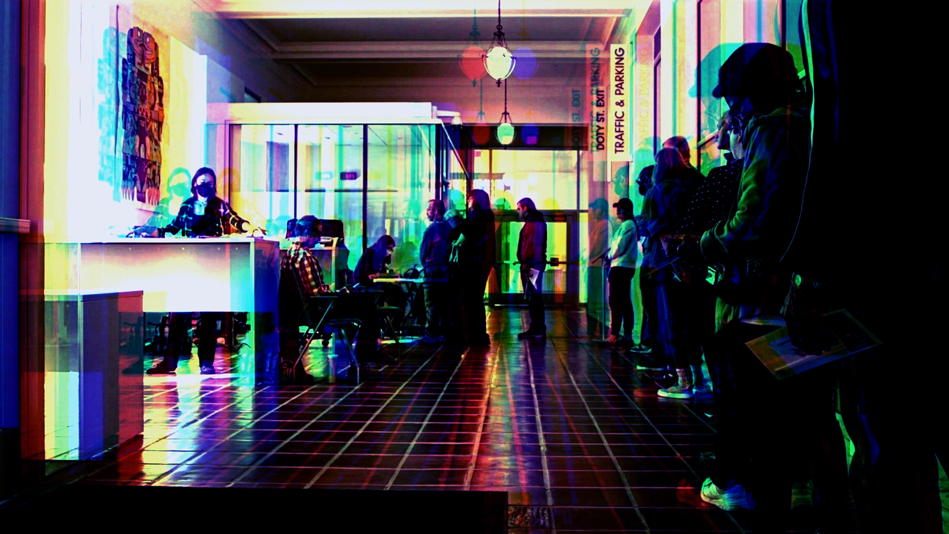 A photo illustration featuring 3-D style dual images in multiple colors shows multiple people standing along a wall in a line that turns toward a table with seated people, in a room with a glass-walled vestibule in the background, hanging light fixtures and a tile floor.