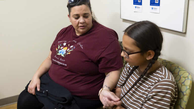 Lynda Hagen holds one of Nate Hagen's braids in her left hand while both sit in chairs in a corner of an examination room.