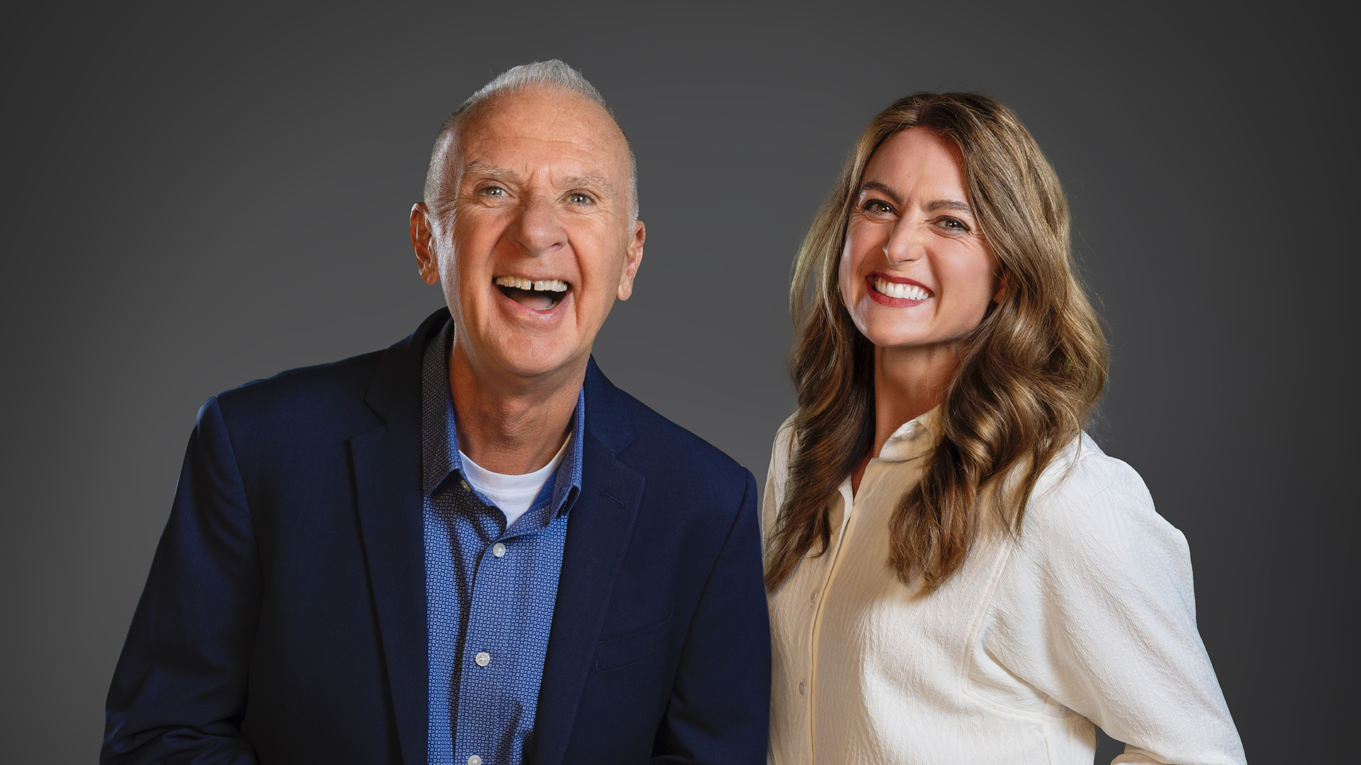 John McGivern dressed in a button-up shirt and blazer smiles at the camera next to a smiling Emmy Fink wearing a blouse and jeans.