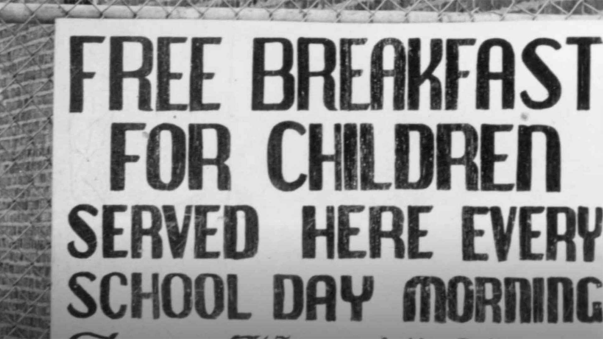 Black and white signage from the era of the Black Panthers Free School Lunch program reads: "Free breakfast for children served here every school day morning."