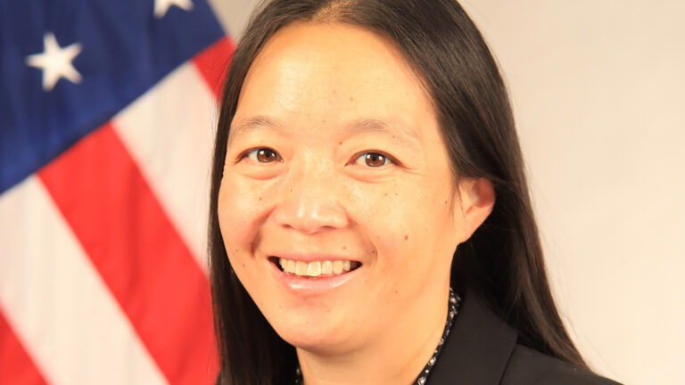 Karyn Hyun poses for a portrait with a U.S. flag in the background.