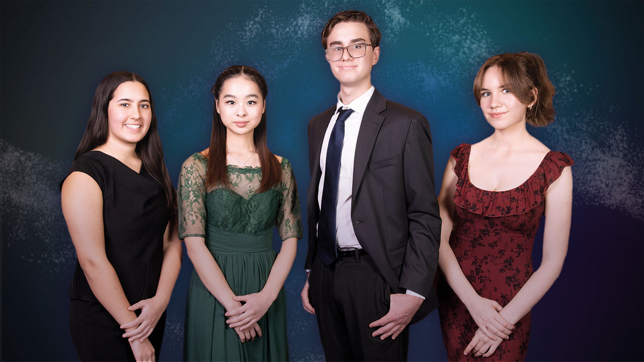 Four teenagers in formal wear smile, posing in front of a blank backdrop.