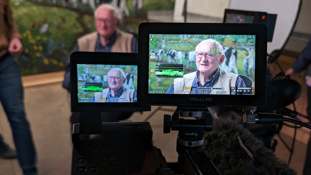 Two small camera displays show a man smiling in frame for an interview.