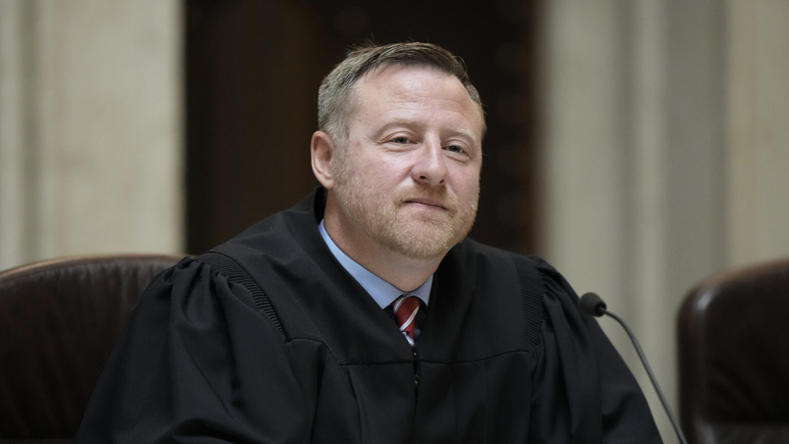 Brian Hagedorn faces a microphone while sitting in a high-backed leather chair.