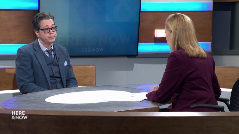 Chad Alan Goldberg and Frederica Freyberg sit facing each other on the Here & Now set.