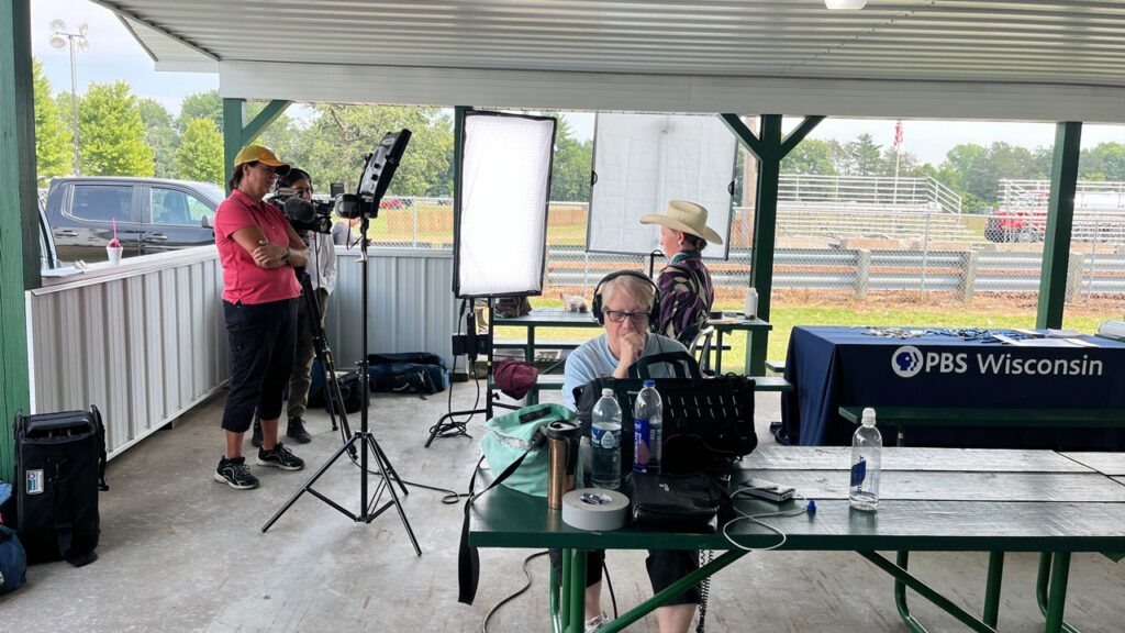 A camera crew interviews someone in a fair ground