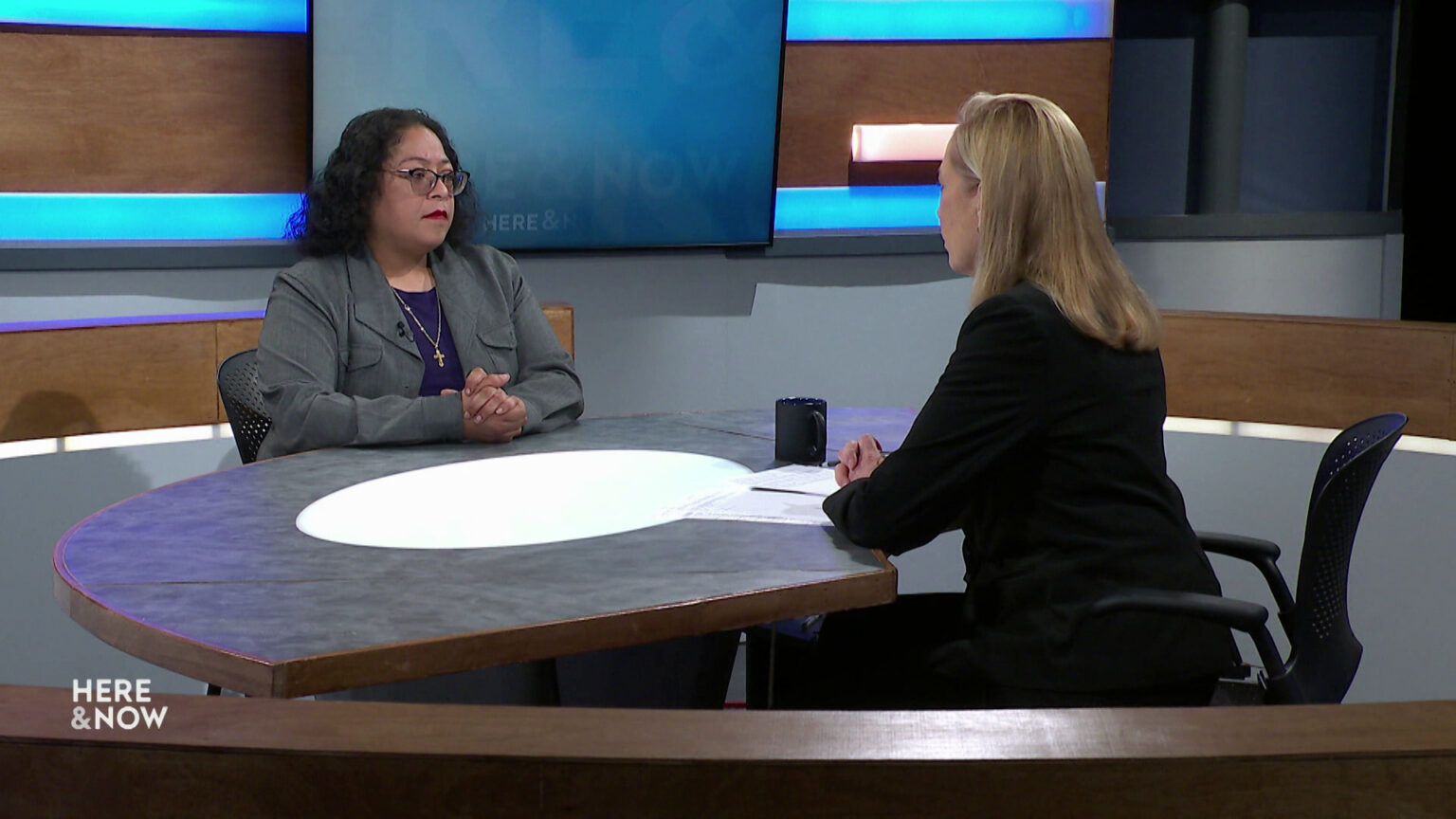 Sylvia Ortiz-Velez and Frederica Freyberg sit facing each other on the Here & Now set.