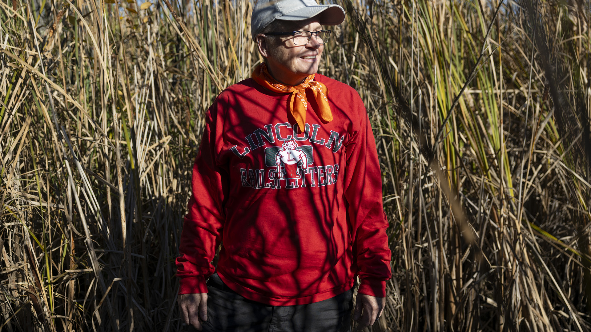 Katie McCullough stands in front of and among stands of head-high reeds and grasses.