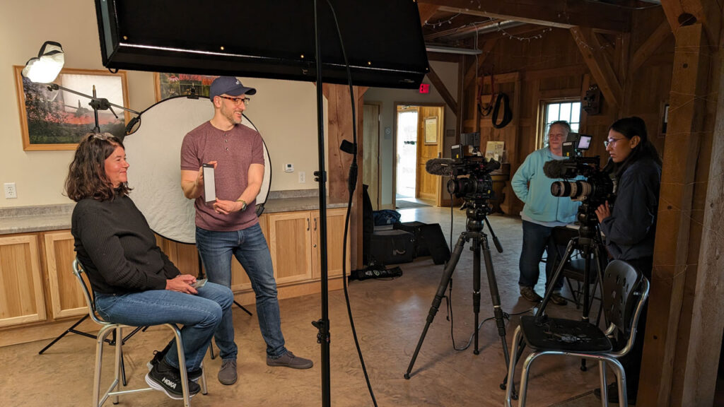 A production crew prepares a set for an interview inside a rustic board room.