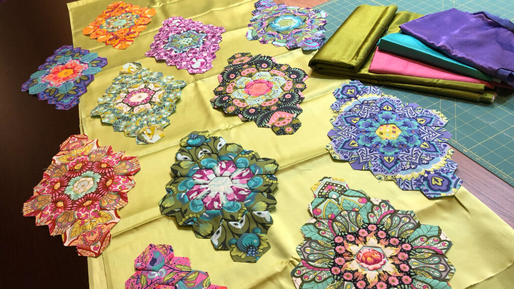 A close-up of hexagon fabric clusters pieced together and arranged on silk.
