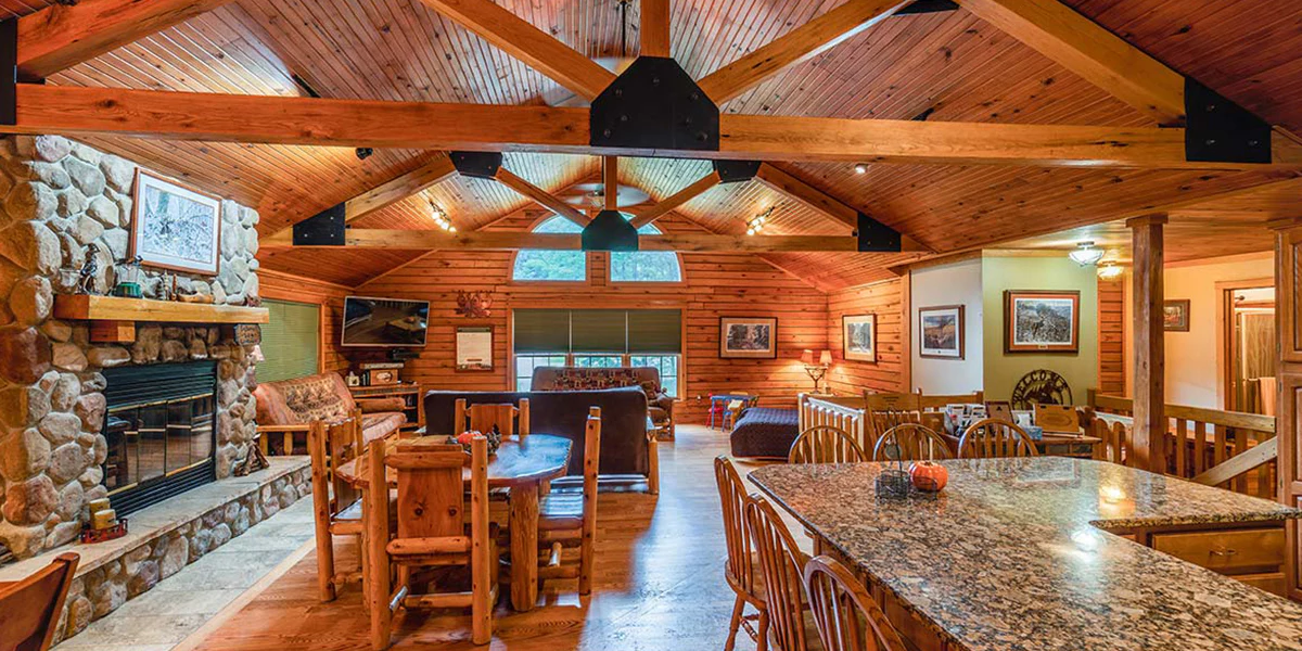 A cozy log home living room and kitchen in a Log Gables property in Lake Delton, Wisconsin, featuring wooden beams and rustic decor, creating a warm, inviting atmosphere.