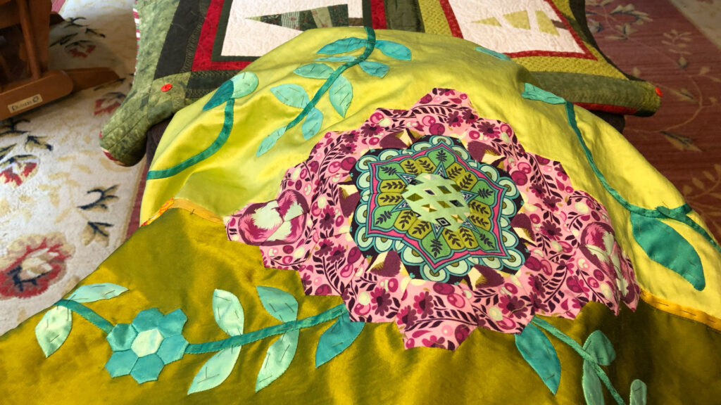 A bright green quilt in progress on someone's knee as it is being constructed. 