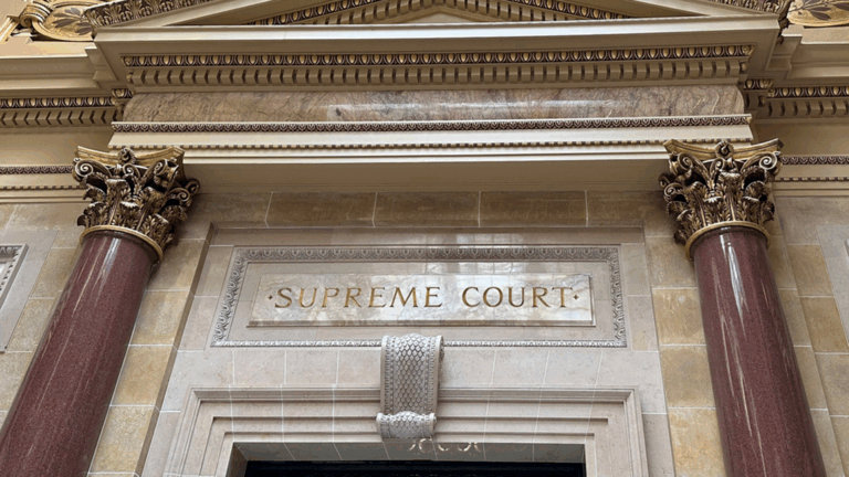 Ornate architectural entrance with red marble columns and gold-accented capitals, featuring the inscription SUPREME COURT.