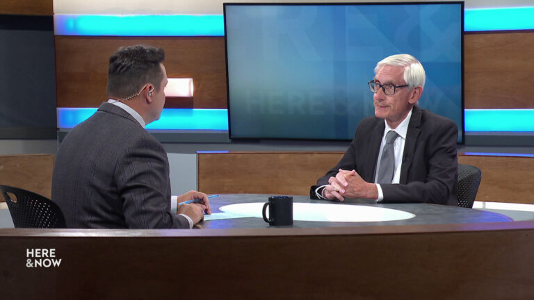 Zac Schultz and Tony Evers sit facing each other on the Here & Now set.