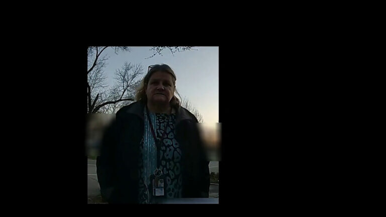 A still image from a video shows a vertical framing of Hannah Dugan standing outdoors with leafless trees in the background, with portions of the image blurred as a redaction.
