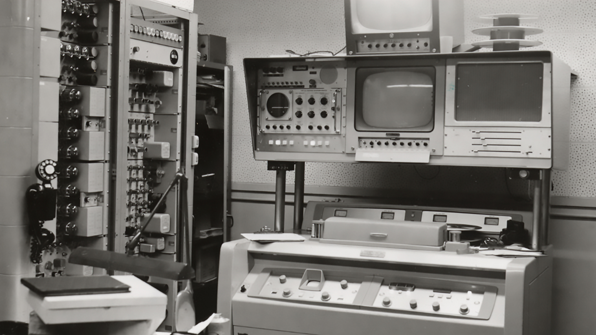 Historic television control room with large analog broadcast equipment, monitors, and a reel-to-reel videotape recorder, circa 1950s.