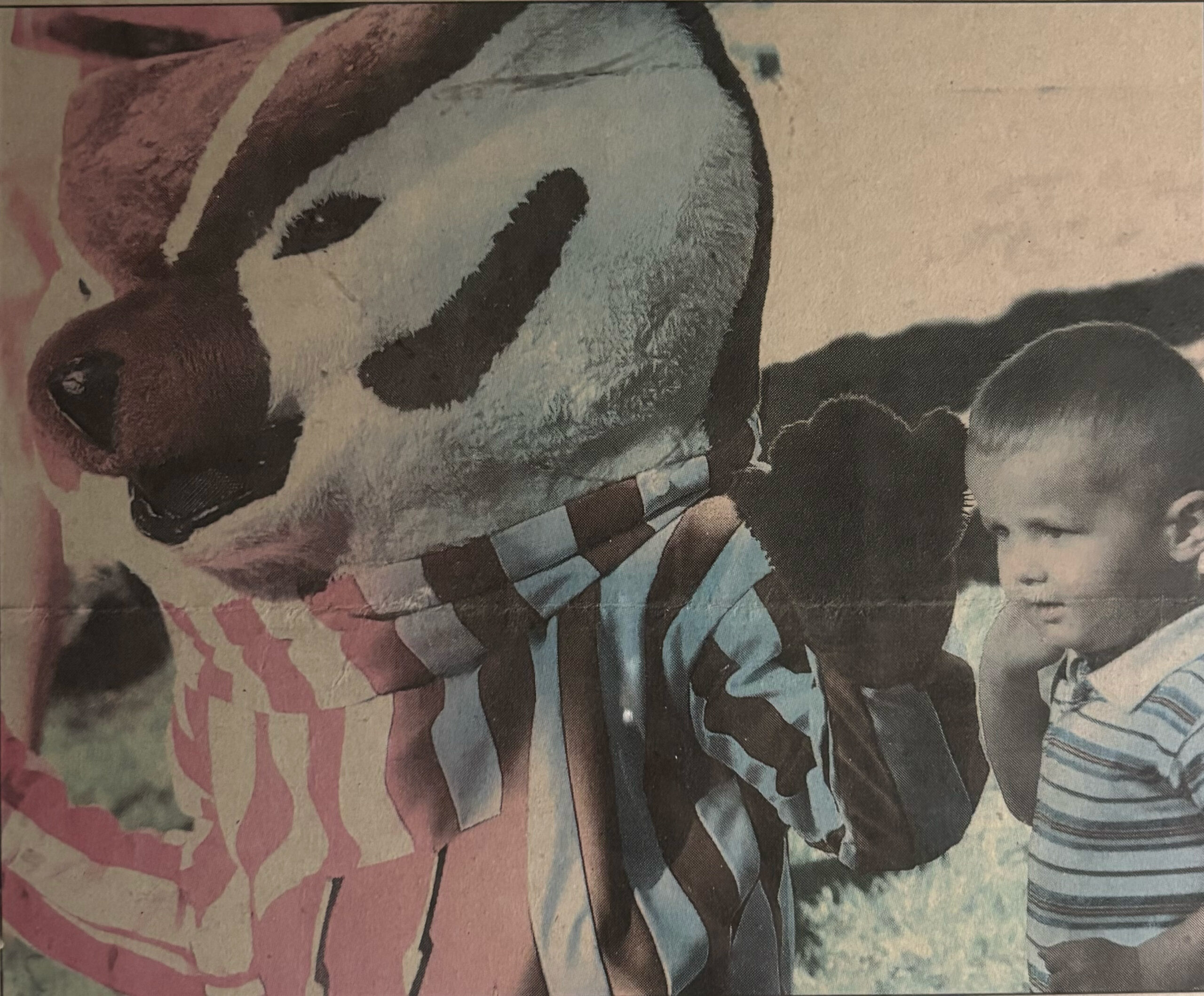 Cecil Powless as a child in a striped shirt stands next to a person in a Bucky Badger mascot costume wearing a striped outfit.