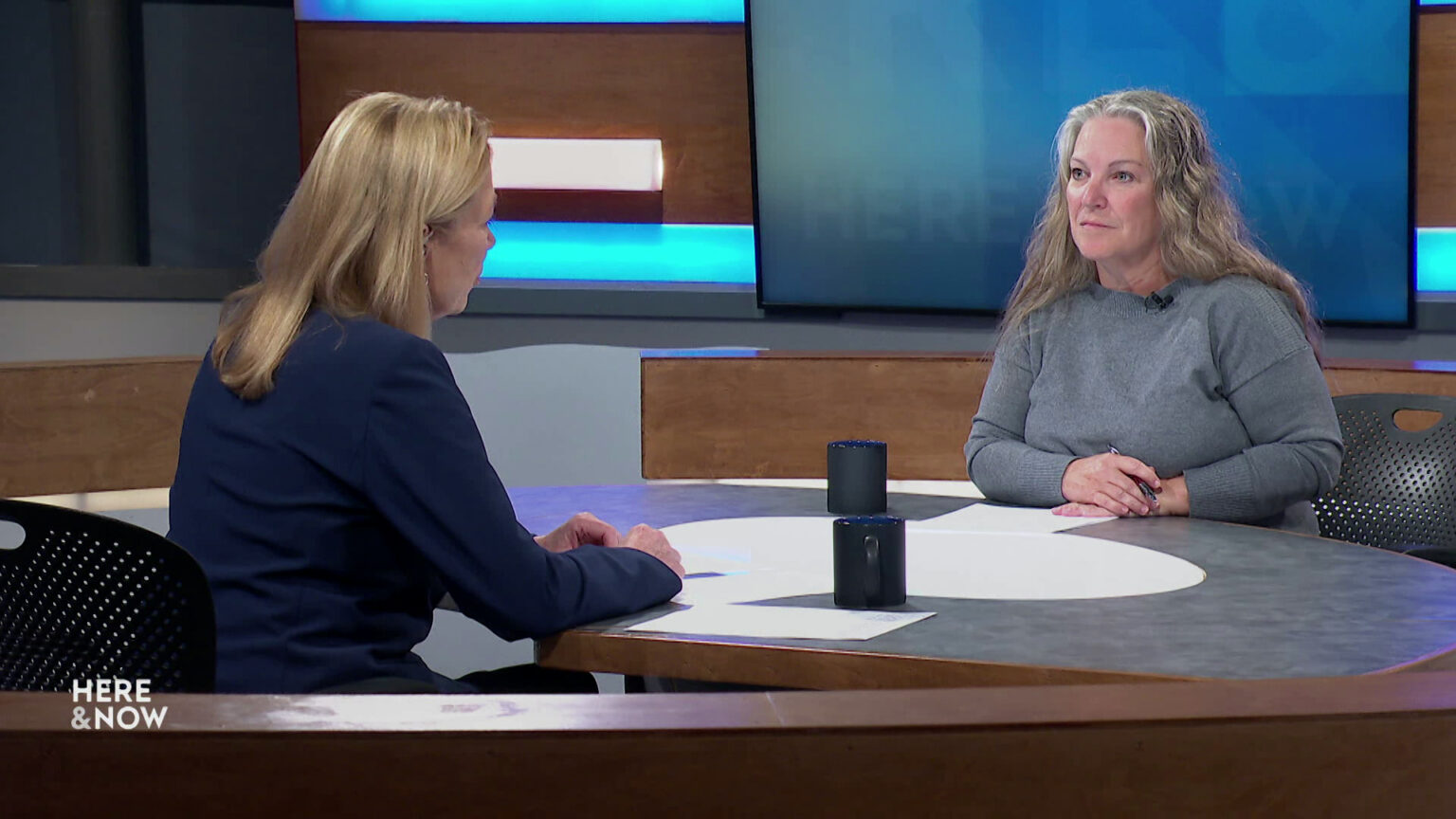 Frederica Freyberg and Jackie Anderson sit facing each other on the Here & Now set.
