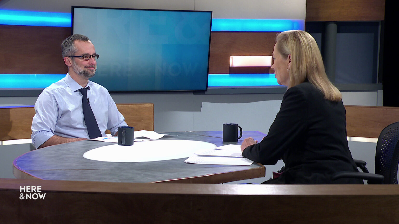 Mark Sommerhauser and Frederica Freyberg sit facing each other on the Here & Now set.