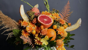 A stunning glamor shot of a flower arrangement featuring fresh fruit such as grapefruit and apple slices.