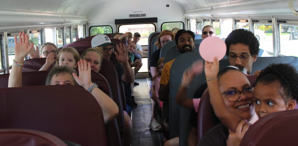 Children and their grown-ups ride on a school bus